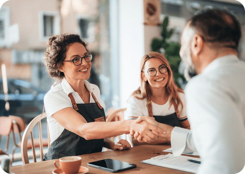 Handshake at a business meeting, smiling participants.